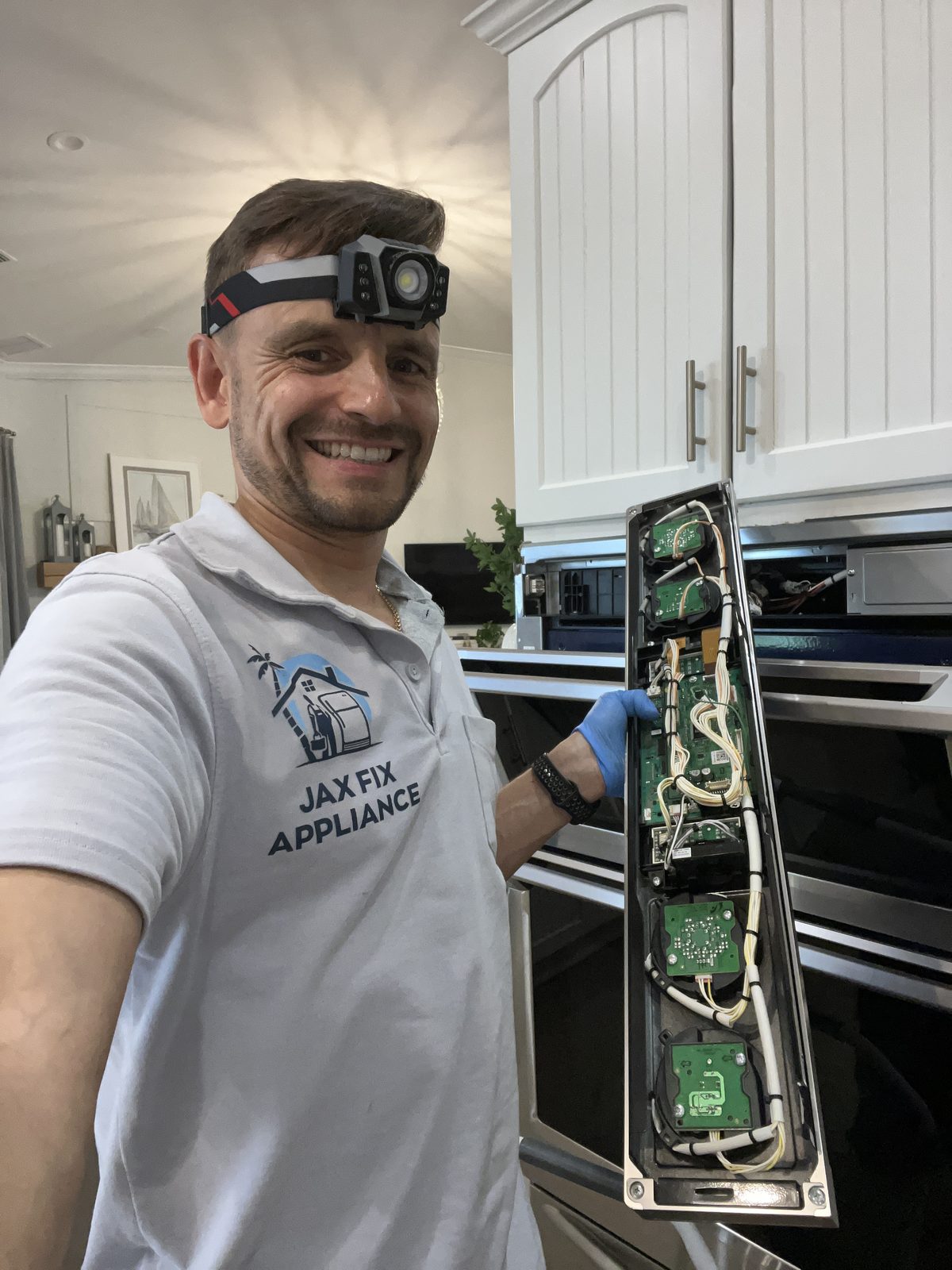 Konstantin holding the control panel of a built-in wall oven during repair