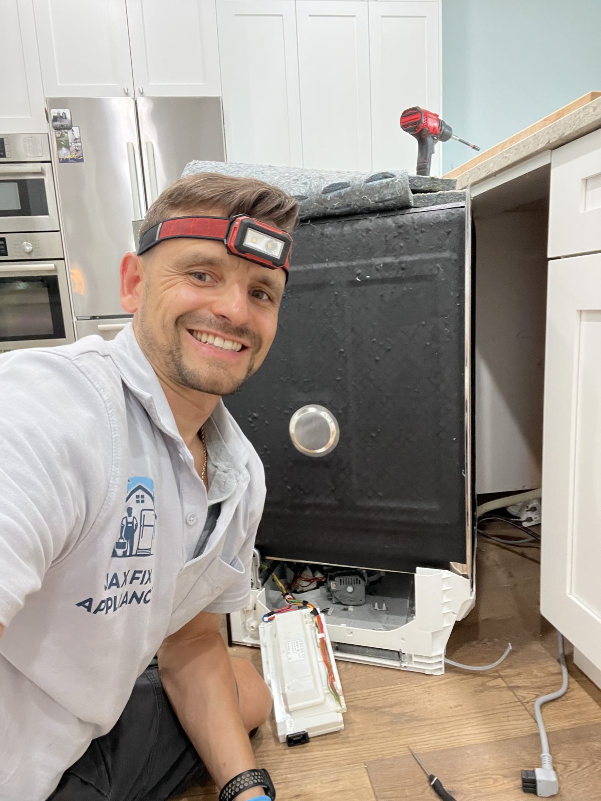 Konstantin behind a dishwasher with the insulation blanket removed during repair