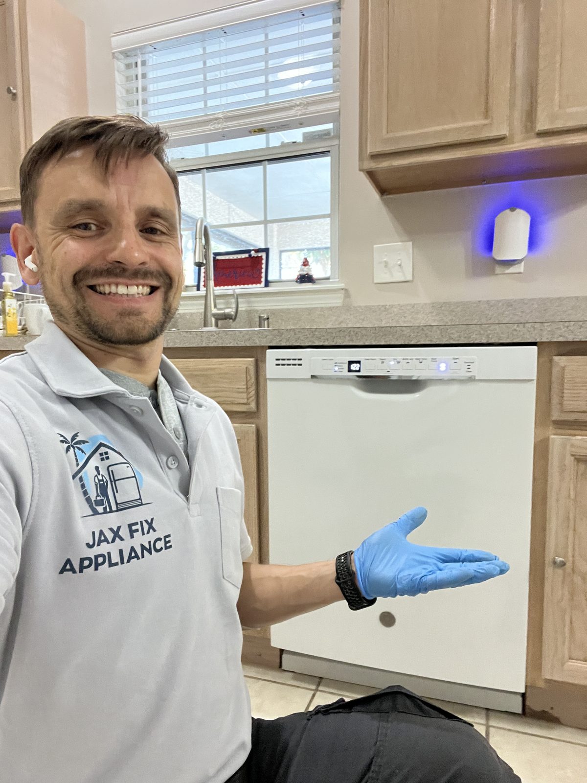 Konstantin presenting a repaired white dishwasher installed under the counter