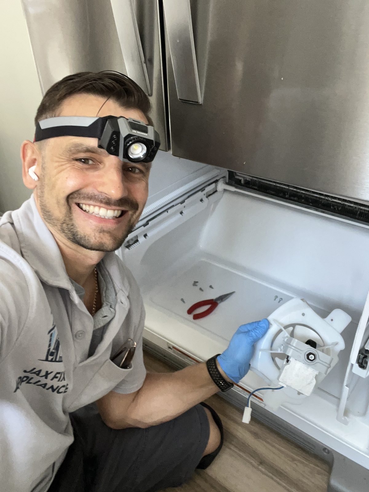 Konstantin repairing the ice maker unit at an open freezer drawer