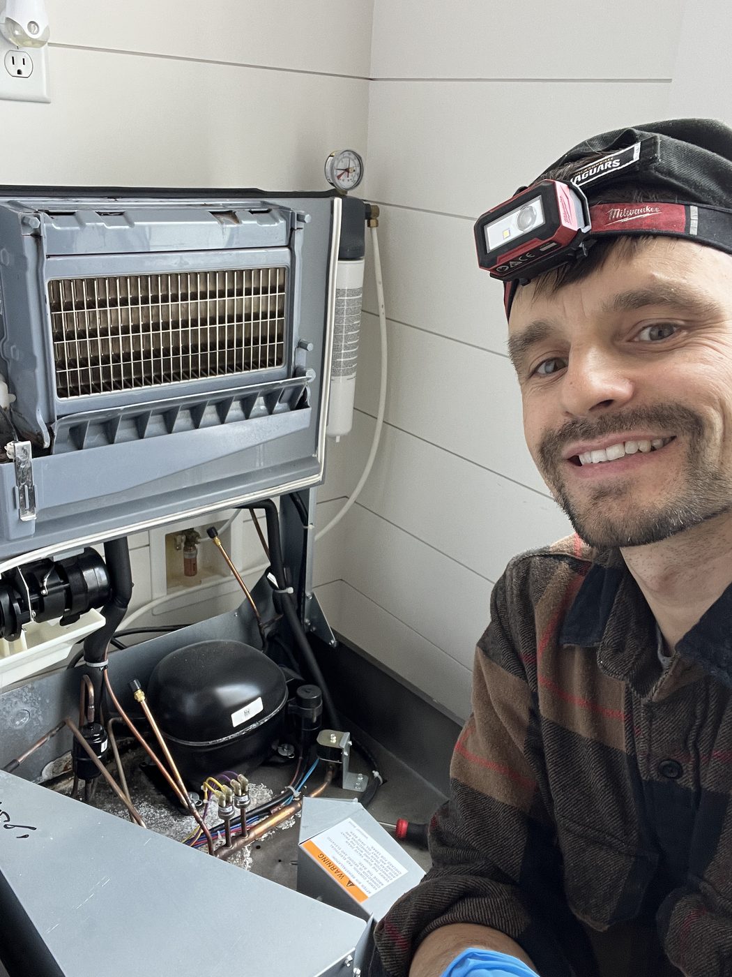 Konstantin servicing a refrigerator compressor in a Jacksonville home