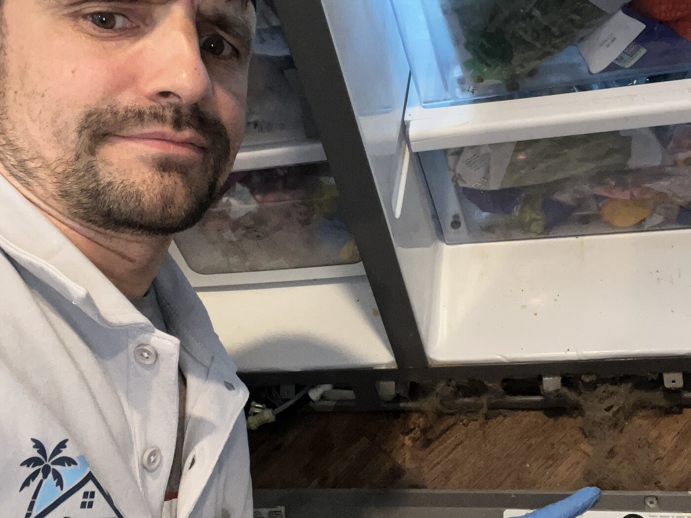 Konstantin in branded Jax Fix Appliance polo at an open french-door refrigerator