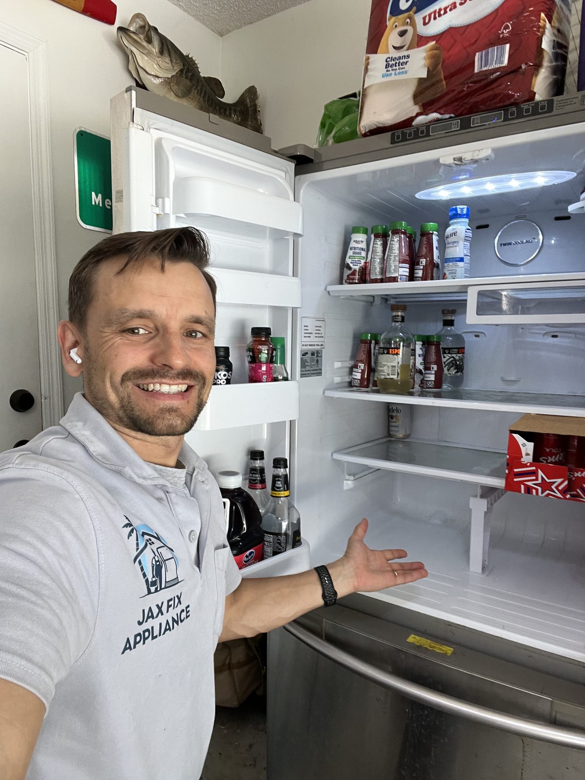 Konstantin in branded Jax Fix Appliance polo presenting a repaired French-door refrigerator