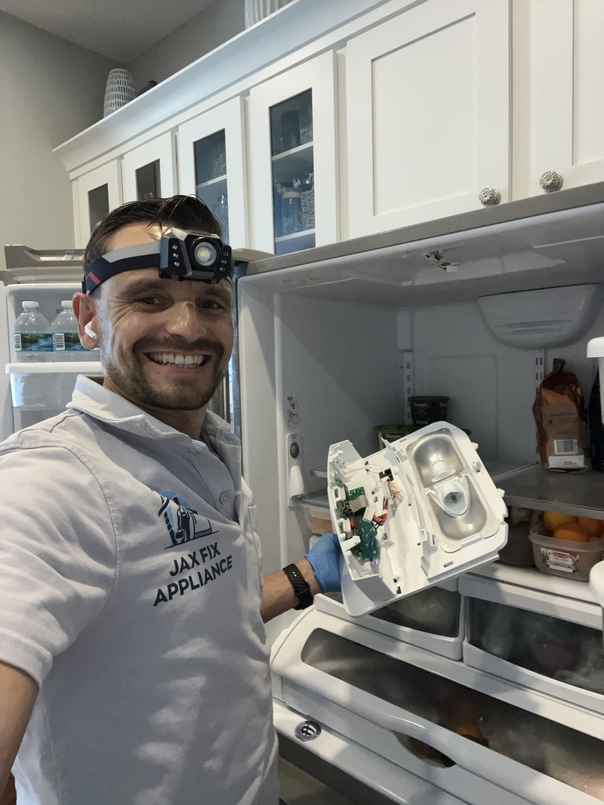 Konstantin holding an ice maker assembly during a French-door refrigerator repair