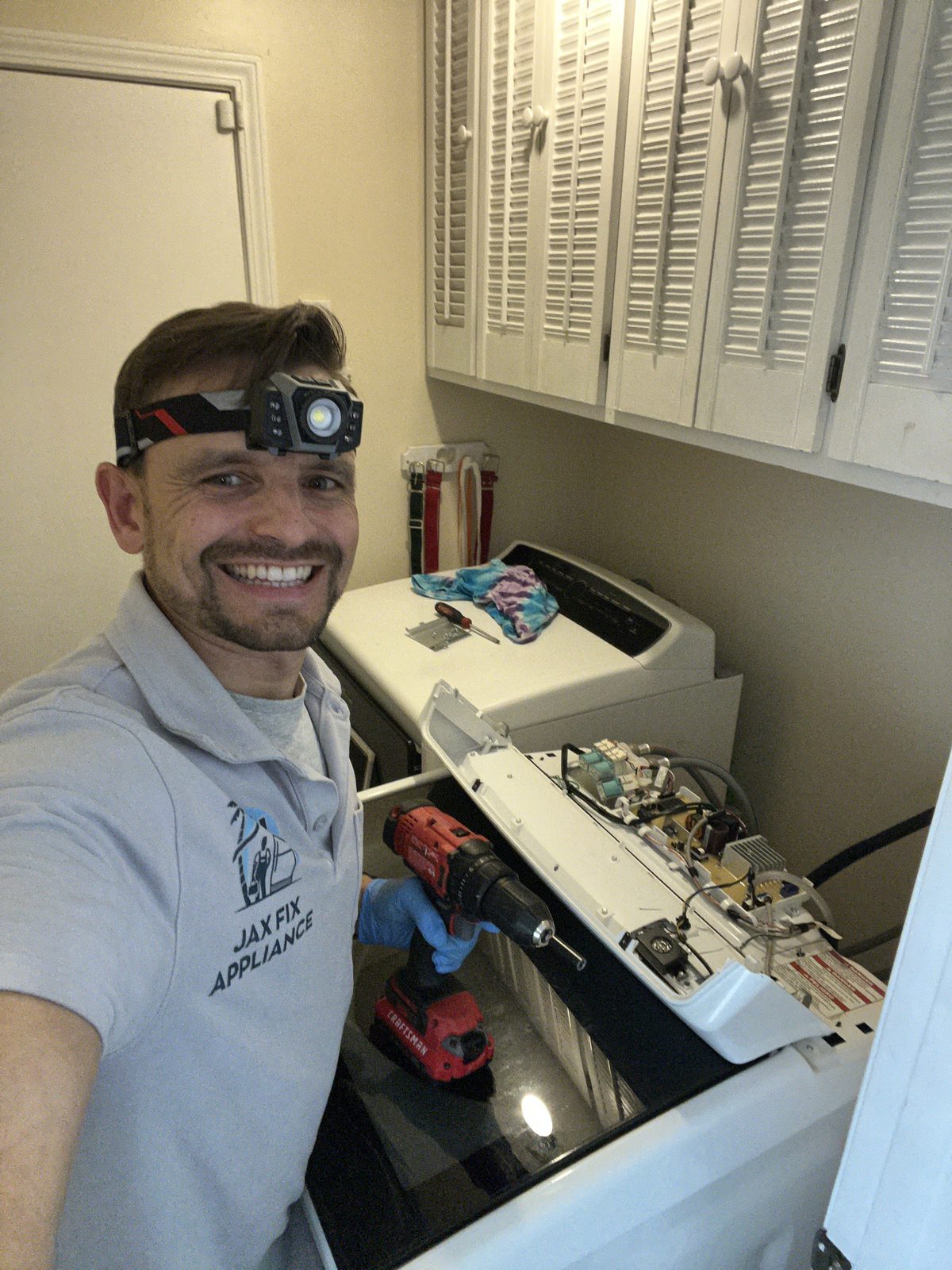 Konstantin at a top-load washer with the control panel opened for diagnostics