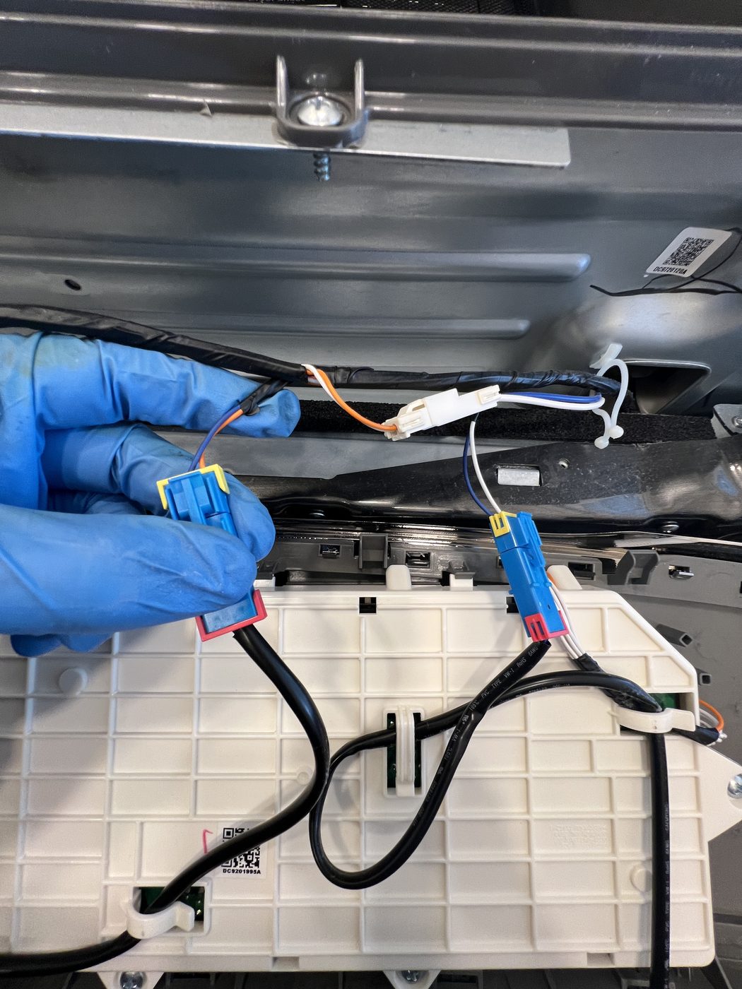 Gloved hand reconnecting dryer wiring harness during repair